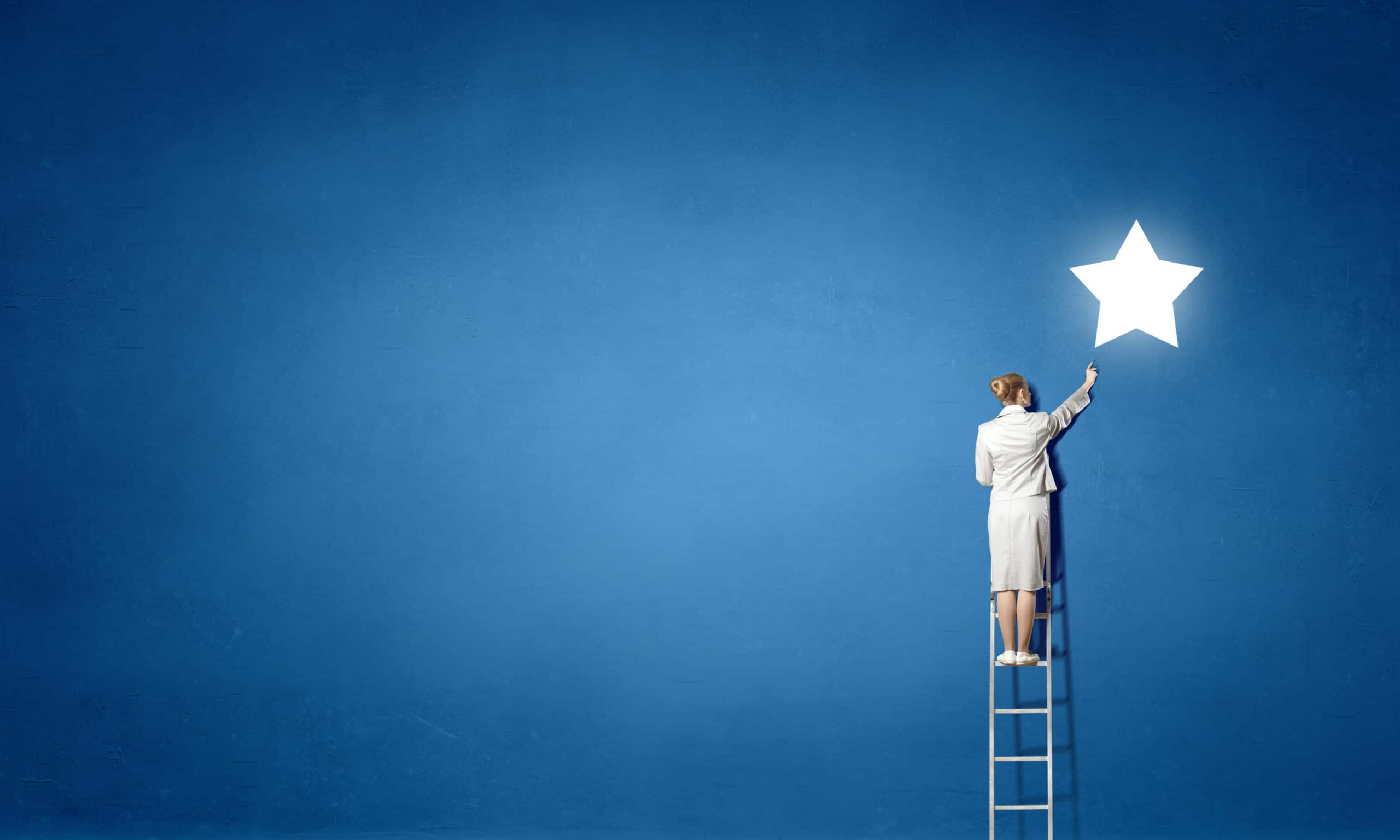 Businesswoman on ladder reaching star